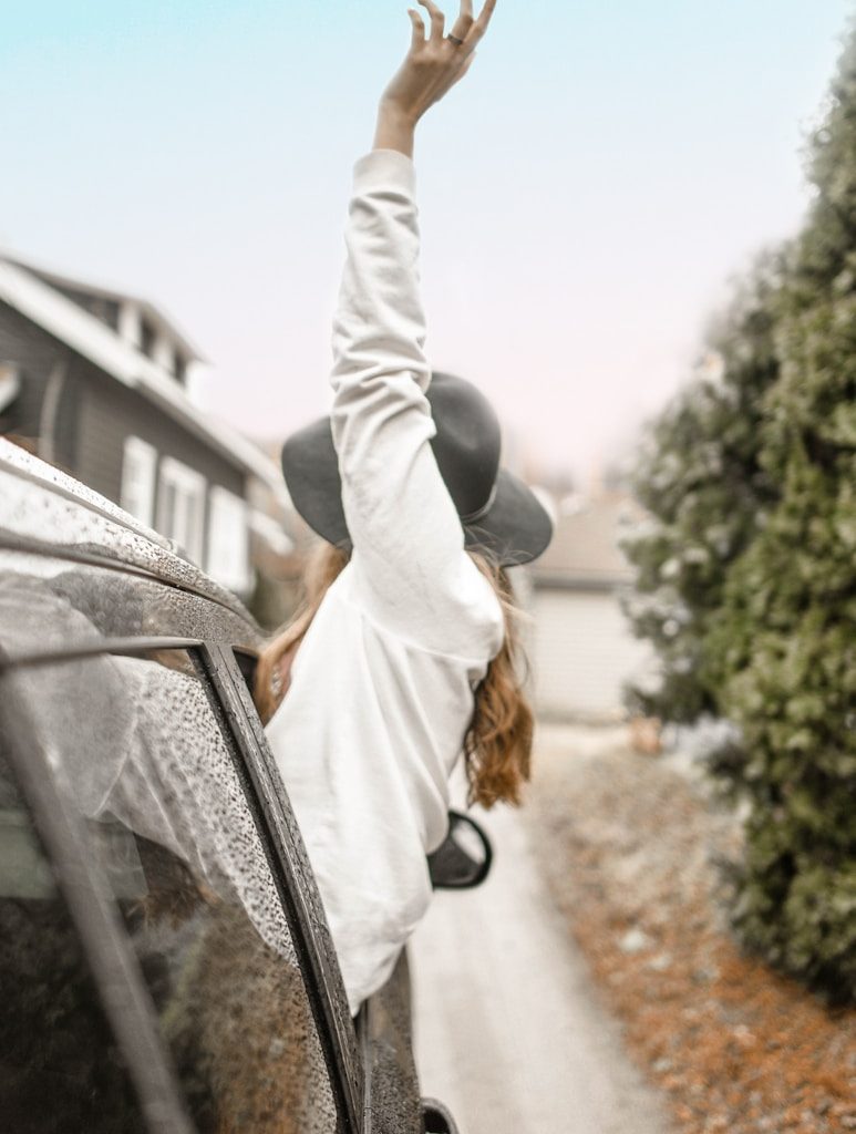 woman rising left hand on vehicle window during daytime