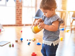 girl in blue denim dungaree pants holding blue and white polka dot handbag