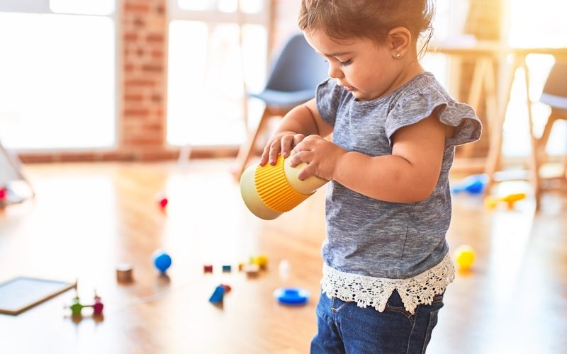 girl in blue denim dungaree pants holding blue and white polka dot handbag