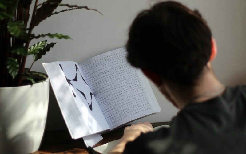 a person sitting at a table reading a book