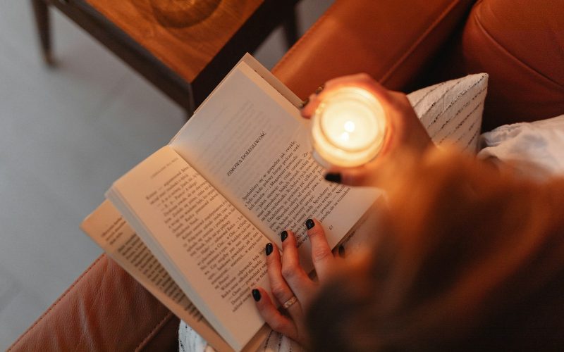 a woman sitting on a couch reading a book