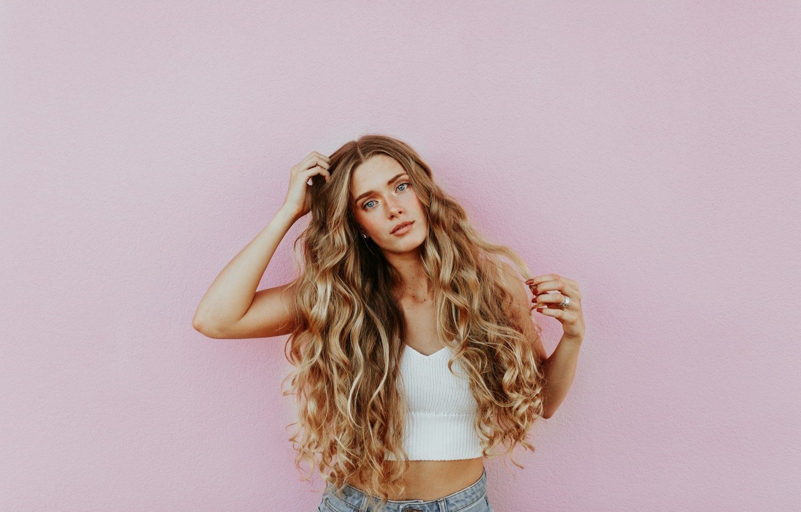 woman standing next to pink wall while scratching her head