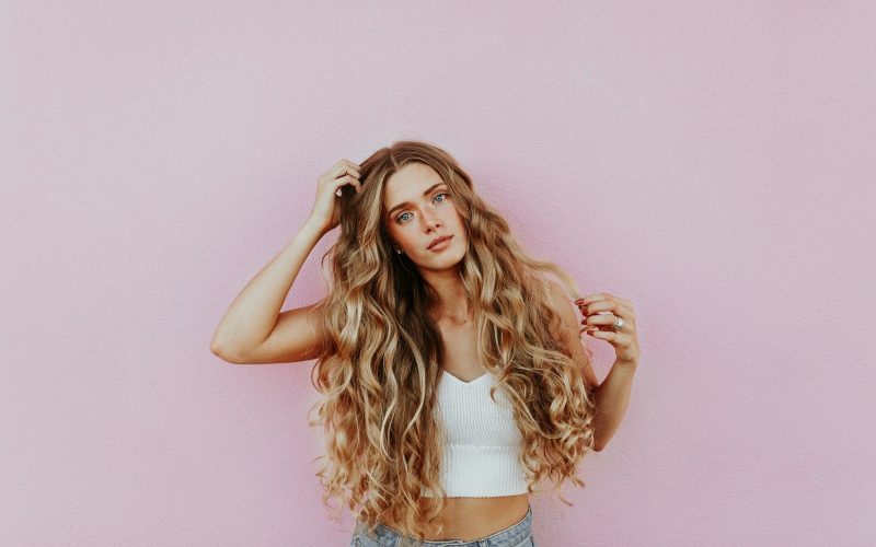 woman standing next to pink wall while scratching her head