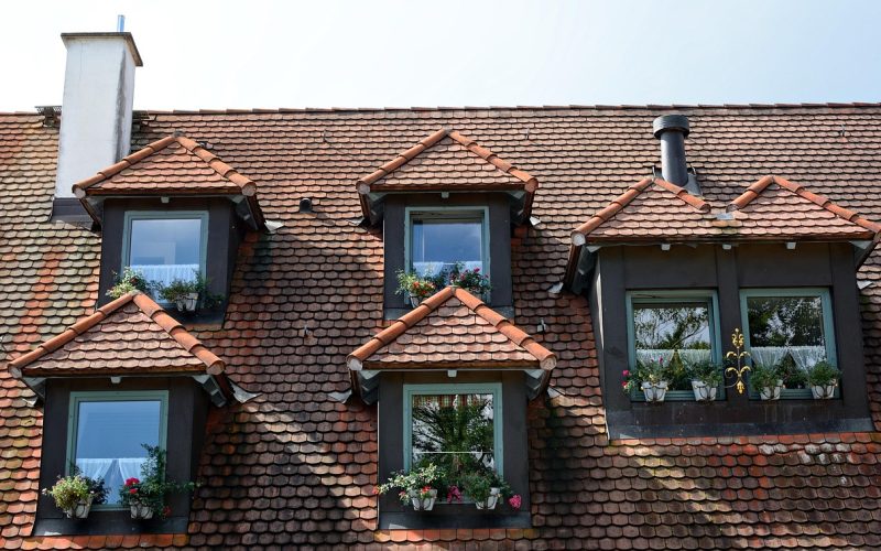 Een dakkapel op het hellende dak van een woonhuis met witte kozijnen