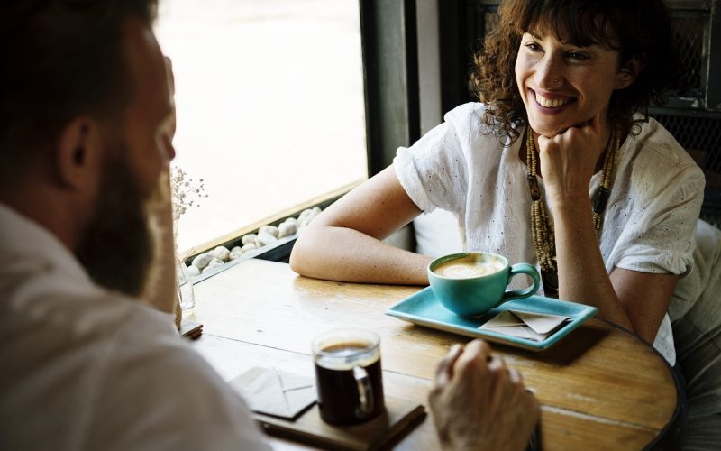 Twee vrienden in gesprek aan een tafel met koffie