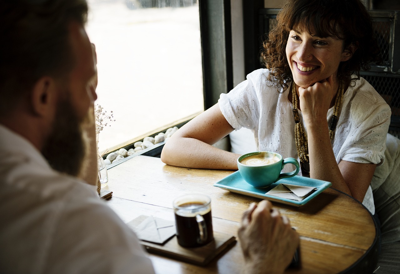 Twee vrienden in gesprek aan een tafel met koffie