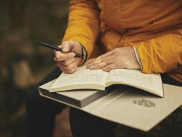 Persoon schrijft een carrièreplan in een notitieboekje aan een bureau