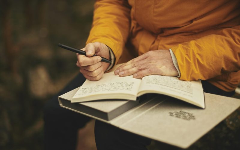 Persoon schrijft een carrièreplan in een notitieboekje aan een bureau