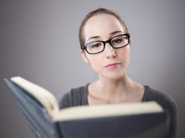 Een student leest aandachtig een literair boek aan een bureau