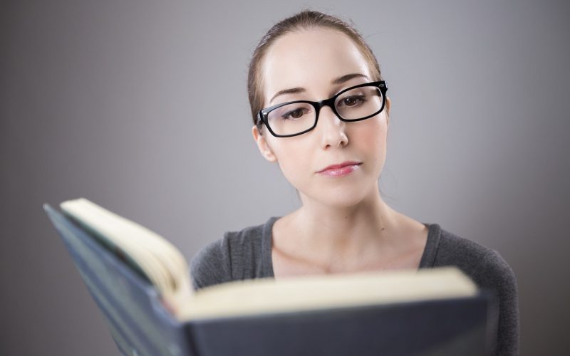 Een student leest aandachtig een literair boek aan een bureau