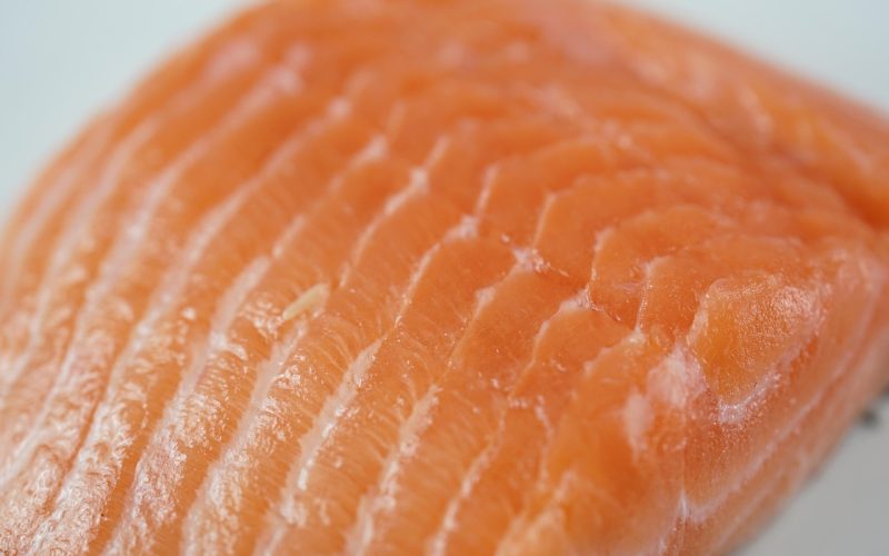 Verse zalmfilet met zichtbare oranje kleur op een houten plank